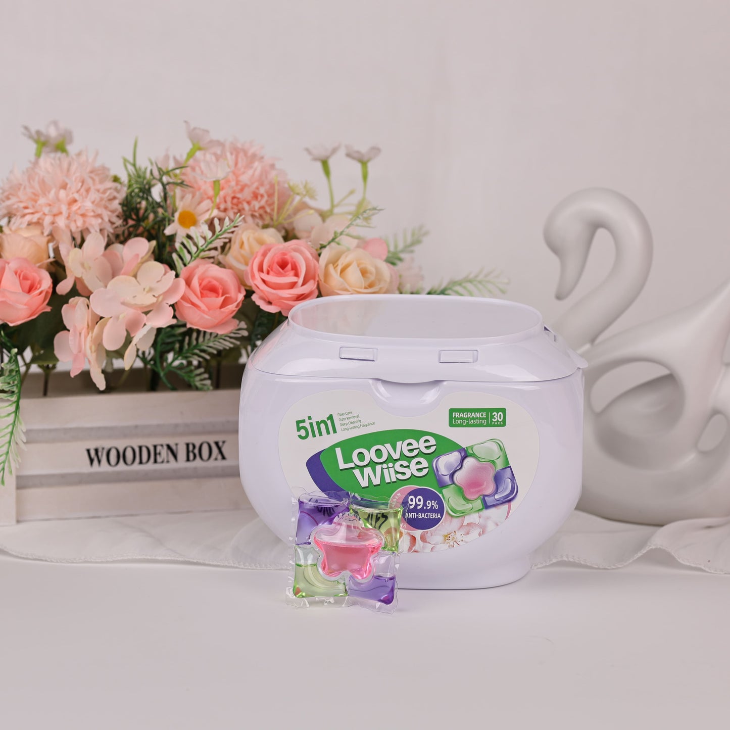5-in-1 tub of Flower Pod laundry pods in Velvet Garden styled beside flowers and a wooden box