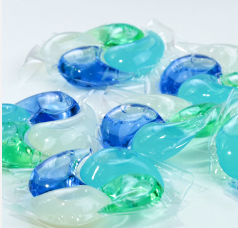 Loose Swirl Pod laundry pods with blue, teal, green and white chambers on a white surface