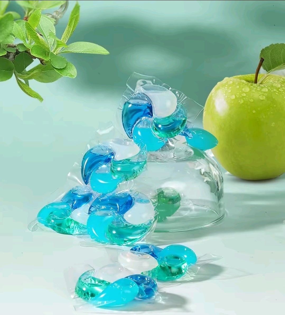 Swirl Pod laundry pods in Crisp Green Fruit, blue and teal pods beside a green apple