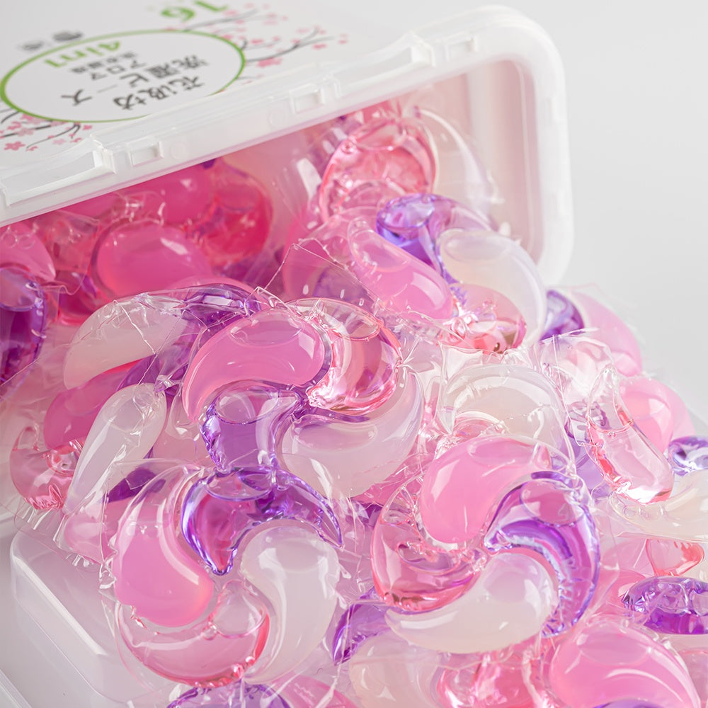 Tub of Sakura Blossom Swirl Pod laundry pods surrounded by scattered pods on a pink background
